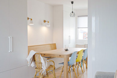 Cette photo montre une petite salle à manger ouverte sur le salon scandinave avec un mur blanc, parquet clair et éclairage.