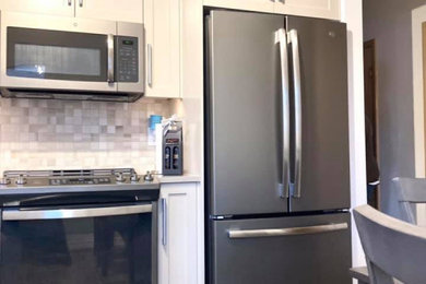 Inspiration for a mid-sized transitional l-shaped vinyl floor and brown floor enclosed kitchen remodel in Other with a double-bowl sink, shaker cabinets, beige cabinets, quartz countertops, beige backsplash, ceramic backsplash, stainless steel appliances and beige countertops
