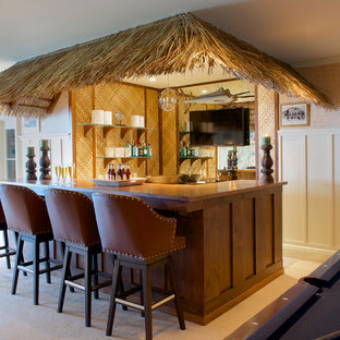 ニューヨークの中サイズのトロピカルスタイルのおしゃれな着席型バー (濃色木目調キャビネット、木材カウンター、ミラータイルのキッチンパネル、カーペット敷き、茶色いキッチンカウンター) の写真