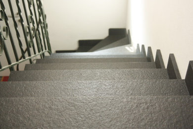 Aménagement d'un escalier courbe moderne de taille moyenne avec des marches en pierre calcaire, des contremarches en pierre calcaire et un garde-corps en métal.