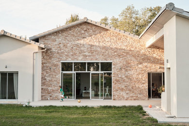 Exemple d'une grande façade de maison tendance en pierre de plain-pied avec un toit en tuile et un toit gris.