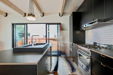 Eat-in kitchen - mid-sized contemporary galley medium tone wood floor eat-in kitchen idea in San Francisco with flat-panel cabinets, white backsplash, stainless steel appliances, an island, an integrated sink, laminate countertops and ceramic backsplash