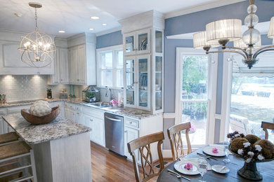 Photo of a mid-sized transitional l-shaped eat-in kitchen in Charleston with raised-panel cabinets, white cabinets, granite benchtops, white splashback and with island.