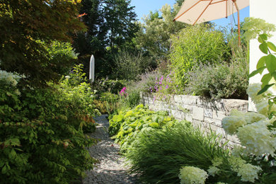 Kleine, Halbschattige Klassische Gartenmauer im Frühling, neben dem Haus mit Natursteinplatten in Berlin
