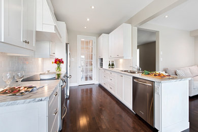 This is an example of a mid-sized transitional galley kitchen pantry in Ottawa with a double-bowl sink, shaker cabinets, white cabinets, soapstone benchtops, white splashback, subway tile splashback, stainless steel appliances, dark hardwood floors, a peninsula and brown floor.