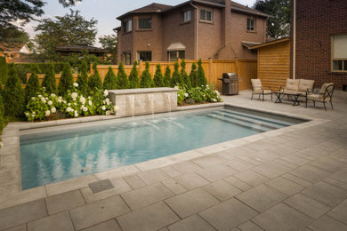 This is an example of a mid-sized contemporary backyard garden in Toronto with with waterfall and natural stone pavers.