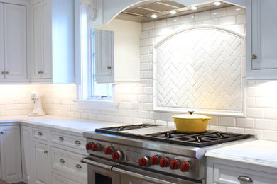 Mid-sized elegant u-shaped dark wood floor kitchen photo in Chicago with recessed-panel cabinets, white cabinets, quartz countertops, white backsplash, subway tile backsplash, stainless steel appliances and an island