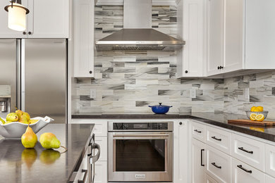 Enclosed kitchen - mid-sized transitional u-shaped medium tone wood floor enclosed kitchen idea in San Francisco with shaker cabinets, white cabinets, granite countertops, gray backsplash, stone tile backsplash, stainless steel appliances and an island