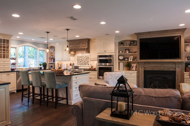 Inspiration for a mid-sized transitional medium tone wood floor and brown floor kitchen remodel in New York with an undermount sink, raised-panel cabinets, white cabinets, granite countertops, white backsplash, subway tile backsplash, stainless steel appliances, an island and black countertops