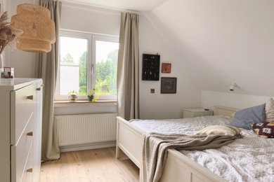 Mittelgroßes Nordisches Schlafzimmer mit weißer Wandfarbe, braunem Holzboden und braunem Boden in Düsseldorf