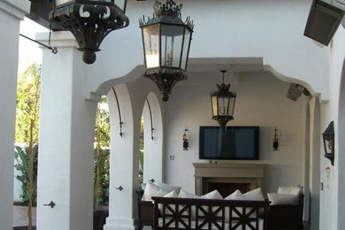 Patio - mid-sized mediterranean backyard tile patio idea in Los Angeles with a fireplace and a roof extension
