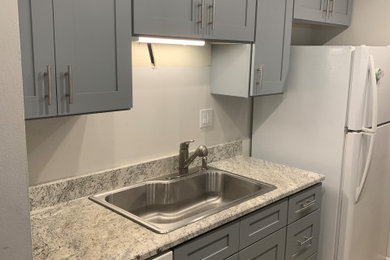 Inspiration for a small modern galley laminate floor and gray floor eat-in kitchen remodel in Chicago with a drop-in sink, shaker cabinets, gray cabinets, granite countertops, white appliances and multicolored countertops