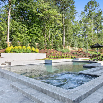 Contemporary style pool with silver travertine deck and custom water feature