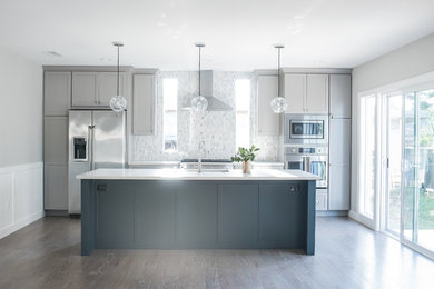 Open concept kitchen - mid-sized transitional galley dark wood floor and brown floor open concept kitchen idea in Los Angeles with an undermount sink, recessed-panel cabinets, gray cabinets, marble countertops, white backsplash, ceramic backsplash, stainless steel appliances, an island and white countertops