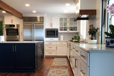 Inspiration for a mid-sized transitional l-shaped medium tone wood floor and brown floor kitchen pantry remodel in Other with an undermount sink, flat-panel cabinets, blue cabinets, quartz countertops, white backsplash, subway tile backsplash, stainless steel appliances, an island and gray countertops