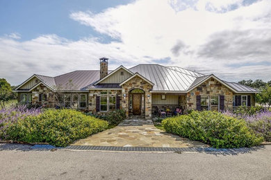 Mid-sized rustic brown one-story stone house exterior idea in Austin with a hip roof and a metal roof