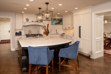 Mid-sized transitional u-shaped eat-in kitchen in Detroit with a single-bowl sink, shaker cabinets, white cabinets, quartz benchtops, white splashback, subway tile splashback, panelled appliances, dark hardwood floors, with island, brown floor and white benchtop.