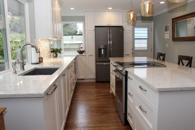 Eat-in kitchen - mid-sized transitional l-shaped medium tone wood floor and brown floor eat-in kitchen idea in Seattle with an undermount sink, recessed-panel cabinets, white cabinets, quartz countertops, multicolored backsplash, ceramic backsplash, stainless steel appliances, an island and white countertops