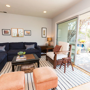 Foto di un piccolo soggiorno costiero aperto con pareti grigie, parquet chiaro, camino classico, cornice del camino in pietra e porta TV ad angolo