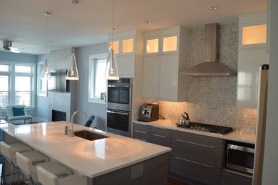 Large minimalist l-shaped medium tone wood floor eat-in kitchen photo in Philadelphia with an undermount sink, flat-panel cabinets, gray cabinets, quartzite countertops, white backsplash, stone tile backsplash, stainless steel appliances and an island