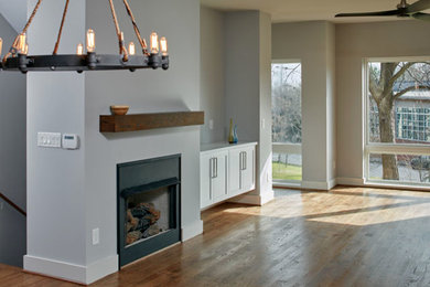 Photo of an expansive industrial open concept family room in Atlanta with grey walls, medium hardwood floors, a standard fireplace, a metal fireplace surround and a wall-mounted tv.