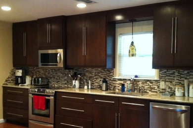 Enclosed kitchen - mid-sized transitional single-wall medium tone wood floor and beige floor enclosed kitchen idea in New Orleans with an undermount sink, flat-panel cabinets, dark wood cabinets, granite countertops, multicolored backsplash, matchstick tile backsplash, stainless steel appliances and no island