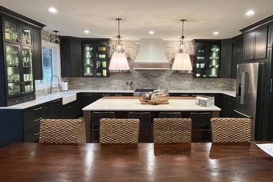 Inspiration for a large cottage u-shaped medium tone wood floor and brown floor open concept kitchen remodel in Detroit with a farmhouse sink, shaker cabinets, black cabinets, quartz countertops, gray backsplash, ceramic backsplash, stainless steel appliances, an island and white countertops
