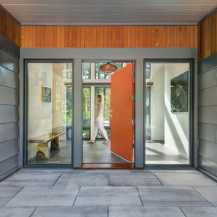 ボストンの片開きドアコンテンポラリースタイルのおしゃれな玄関ドア (オレンジのドア、グレーの床) の写真