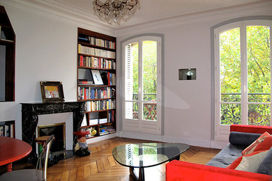 Inspiration pour une petite salle de séjour bohème ouverte avec un mur gris, un sol en bois brun, une cheminée standard, une bibliothèque ou un coin lecture, un manteau de cheminée en pierre et un téléviseur encastré.