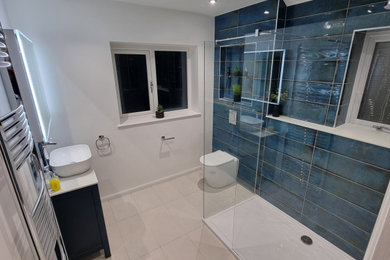 На фото: большая детская ванная комната в современном стиле с фасадами в стиле шейкер, синими фасадами, открытым душем, унитазом-моноблоком, синей плиткой, керамической плиткой, белыми стенами, полом из керамогранита, раковиной с несколькими смесителями, мраморной столешницей, белым полом, открытым душем, разноцветной столешницей, акцентной стеной, тумбой под одну раковину и напольной тумбой с