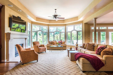 Large mid-century modern open concept medium tone wood floor and beige floor living room photo in DC Metro with beige walls, a standard fireplace, a plaster fireplace and a wall-mounted tv