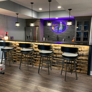 Lower Level Bar With Whiskey Barrel Planks, Gray Cabinets, and Black Quartz