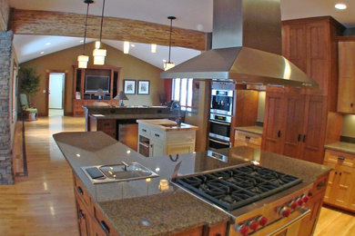 Open concept kitchen - large craftsman u-shaped medium tone wood floor open concept kitchen idea in Minneapolis with a double-bowl sink, shaker cabinets, medium tone wood cabinets, granite countertops, gray backsplash, stainless steel appliances and two islands