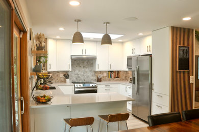 Eat-in kitchen - mid-sized transitional u-shaped light wood floor and brown floor eat-in kitchen idea in Minneapolis with an undermount sink, flat-panel cabinets, white cabinets, gray backsplash, cement tile backsplash, stainless steel appliances, a peninsula and beige countertops