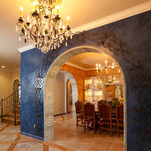 Diseño de distribuidor bohemio con paredes azules, suelo de travertino, puerta simple y puerta de madera en tonos medios