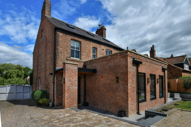 Mid-sized contemporary one-storey brick red house exterior in Other with a flat roof and a mixed roof.
