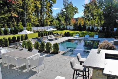 Large contemporary backyard rectangular lap pool in New York with a hot tub and natural stone pavers.