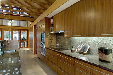 サンフランシスコにあるお手頃価格の広いコンテンポラリースタイルのおしゃれなキッチン (シングルシンク、フラットパネル扉のキャビネット、淡色木目調キャビネット、御影石カウンター、緑のキッチンパネル、石スラブのキッチンパネル、シルバーの調理設備、磁器タイルの床、ベージュの床、緑のキッチンカウンター) の写真