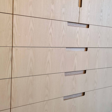 Ash bespoke wardrobes with finger pull handle details and vanity section.
