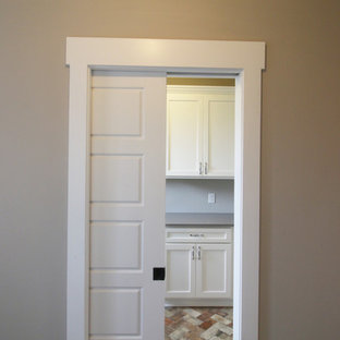 アトランタの中サイズのカントリー風おしゃれな洗濯室 (シェーカースタイル扉のキャビネット、白いキャビネット、御影石カウンター、ベージュの壁、レンガの床) の写真