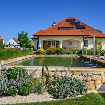 Naturpool mit Natursteinmauer und blühender Gartenkulisse