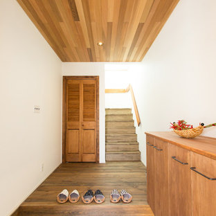 他の地域のおしゃれな玄関 (白い壁、茶色い床) の写真