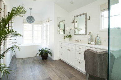 Elegant dark wood floor and brown floor freestanding bathtub photo in Los Angeles with shaker cabinets, white cabinets, white walls and an undermount sink