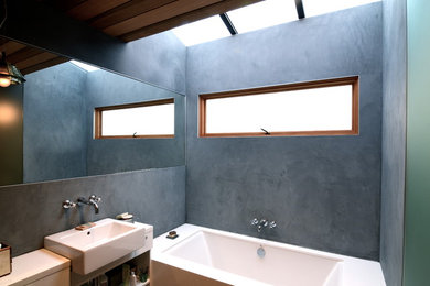Design ideas for a small master bathroom in San Francisco with a drop-in tub, multi-coloured walls, a wall-mount sink, blue floor and beige benchtops.