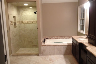 Drop-in bathtub - large traditional master beige tile and porcelain tile porcelain tile drop-in bathtub idea in Detroit with an undermount sink, raised-panel cabinets, black cabinets, marble countertops, a one-piece toilet and beige walls
