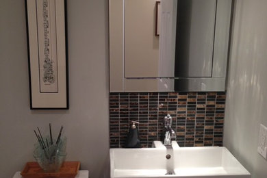 Small trendy brown tile and mosaic tile powder room photo in Toronto with an integrated sink, flat-panel cabinets, dark wood cabinets, a two-piece toilet and gray walls