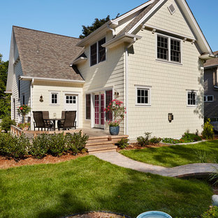 На фото: двухэтажный фасад дома среднего размера желтого цвета в стиле современная классика с двускатной крышей и облицовкой из дерева с