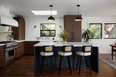 Eat-in kitchen - mid-sized mediterranean medium tone wood floor and brown floor eat-in kitchen idea in Other with a farmhouse sink, flat-panel cabinets, dark wood cabinets, quartz countertops, multicolored backsplash, mosaic tile backsplash, paneled appliances, white countertops and an island