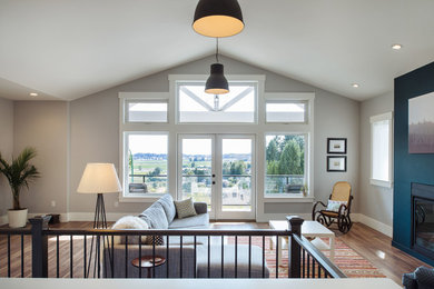 Arts and crafts open concept medium tone wood floor living room photo in Vancouver with gray walls, a standard fireplace, a plaster fireplace and a concealed tv