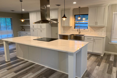 Eat-in kitchen - large cottage laminate floor and gray floor eat-in kitchen idea in Denver with a farmhouse sink, shaker cabinets, white cabinets, quartz countertops, white backsplash, ceramic backsplash, stainless steel appliances, an island and white countertops